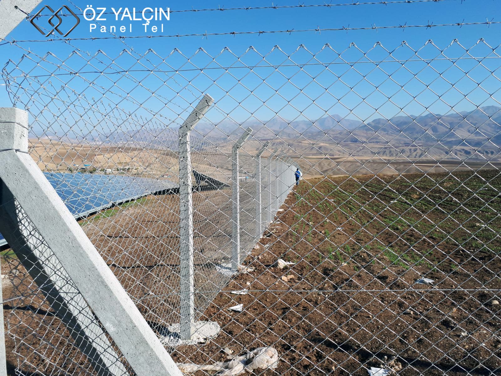 Galvanised woven wire mesh line with barbed wire cranked arms at the CW Enerji solar plant