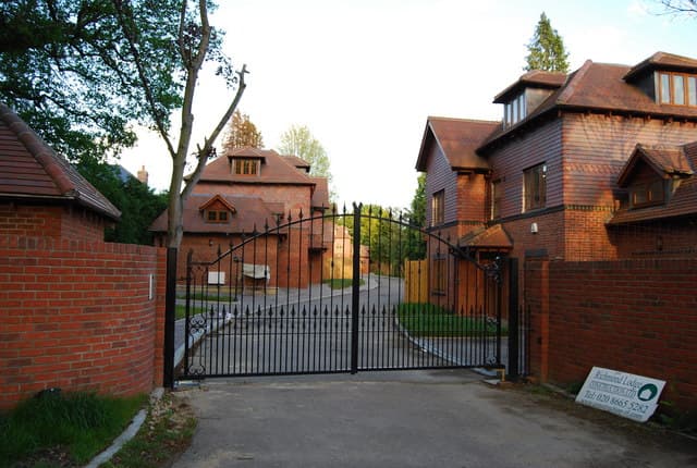 Decorative black garden gate enclosing the entrance to a modern house